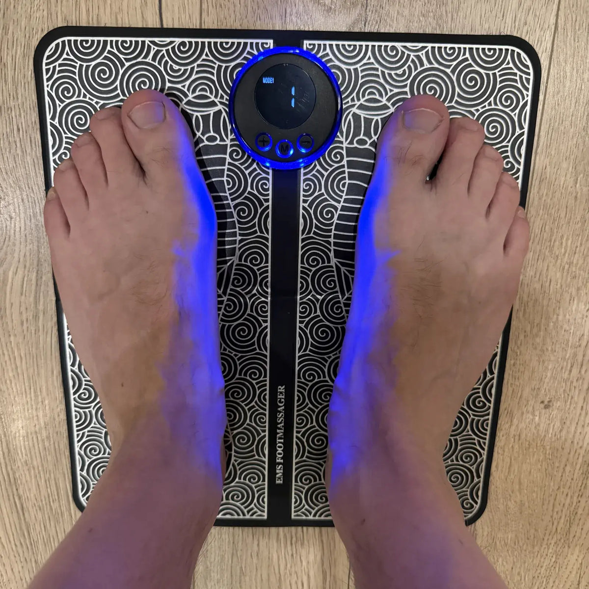 Bare feet on the RELIPROCARE EMS foot mat with the controller on